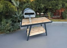 an outdoor bbq grill on top of a wooden table