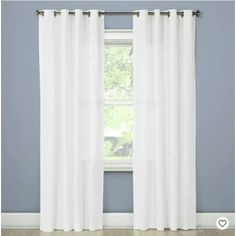 a white curtain hanging on the side of a window in front of a blue wall