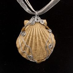 a necklace made out of wire with a shell on it's side and a ribbon around the neck