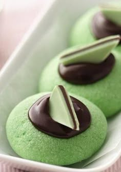 some green cookies with chocolate icing in a white dish