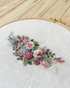 a close up of a embroidery on a wooden hoop with flowers and leaves in it