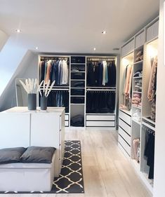 a walk in closet filled with lots of clothes and furniture next to a white couch