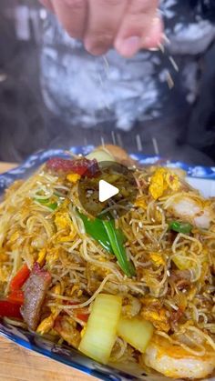 someone is sprinkling some food with chopsticks on top of a plate