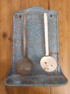 two spoons and a strainer sitting on a blue tray with wood flooring