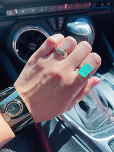 a woman's hand on the steering wheel of a car with a green ring