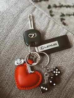 a red heart shaped keychain sitting on top of a couch next to a black and white dice