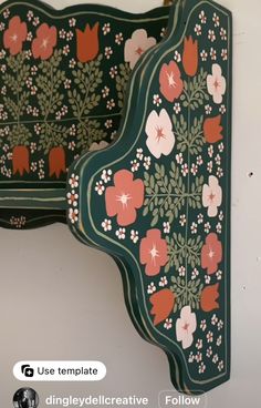 two green and red wall hangings with floral designs on the sides, one has flowers