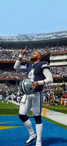 a football player is standing on the field with his hands in the air while holding a ball