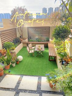 a small garden with wooden benches and potted plants on the grass, in front of a cityscape