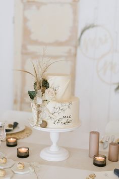 a table topped with a white cake covered in frosting and surrounded by small candles