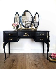 a black dresser with two mirrors on top of it