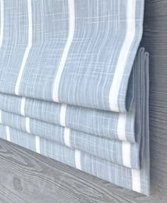 a close up view of a blue and white striped curtain with wood planks in the background