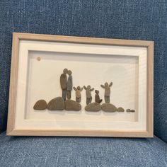 the family is made out of rocks and placed in a frame on a blue couch