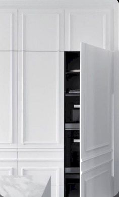 an open refrigerator in a white kitchen next to a counter top oven and cabinets with drawers