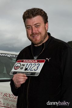 a man holding up a license plate in front of a van