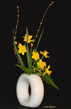 a white vase with yellow flowers in it