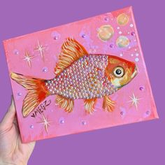 a painting of a goldfish on pink paper with bubbles and sparkles around it