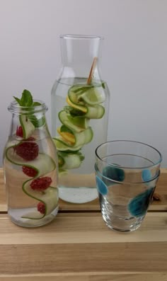 two glass vases filled with cucumbers and raspberries