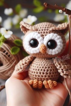 a small crocheted owl sitting on top of a persons hand