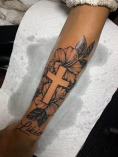 a person with a cross and flowers on their arm