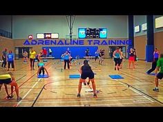 a group of people standing on top of a wooden floor in a gym with blue mats