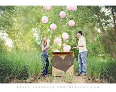 a man and woman standing in front of a box with balloons floating from it on the ground