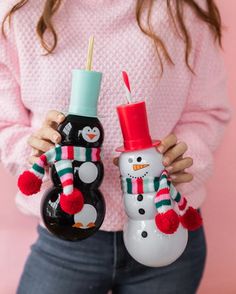 a woman holding two snowmen in their hands and one is wearing a pink sweater