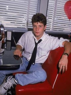 a young man sitting in a red chair