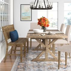 a dining room table and chairs with flowers in the center on an area rug that looks like wood