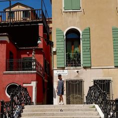 there is a man that is walking down the stairs in front of some buildings with green shutters