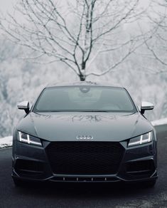 a car parked on the side of a road in front of a snow covered tree