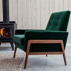 a green chair sitting in front of a fire place next to a wooden burning stove