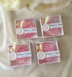 three wedding favors in pink and white with gold accents on the front, one for each guest