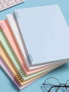 a stack of notebooks sitting on top of a blue desk next to a keyboard