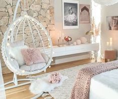 a bedroom with a white bed and hanging chair next to a stone wall in the corner