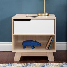 a blue pig figurine sitting on top of a wooden shelf next to a lamp