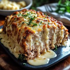 a piece of meatloaf covered in gravy and melted cheese on a plate