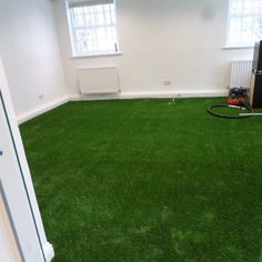 an empty room with green grass and a vacuum