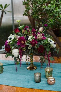 a vase filled with flowers sitting on top of a blue table cloth next to candles