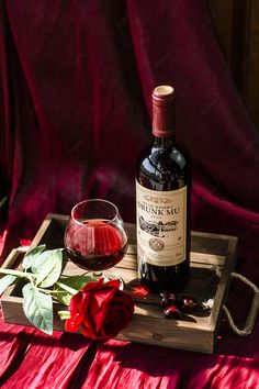 a bottle of wine sitting on top of a wooden tray next to a glass filled with liquid