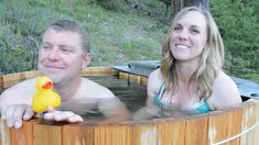 a man and woman sitting in a hot tub with rubber ducky on the side