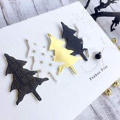 some black and gold christmas decorations on a white card with glitter stars in the background