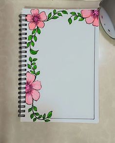 a notebook with pink flowers on it next to a computer mouse