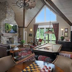 a living room filled with furniture and a pool table in front of a fire place