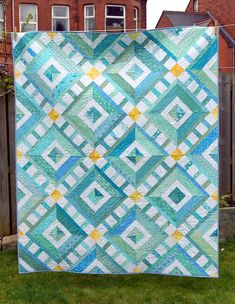 a blue and yellow quilt is hanging on a fence in front of a brick building