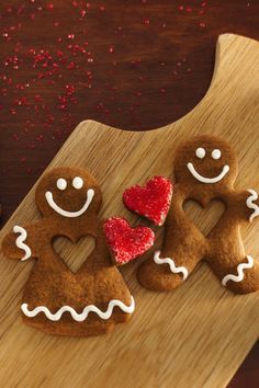 three decorated gingerbreads on a wooden cutting board