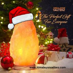 a himalayan salt lamp with santa's hat on it and presents around the tree