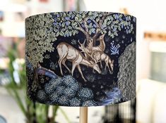 a lampshade with two deers and trees on it