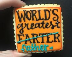 a hand holding a decorated cookie with the words world's greatest father on it