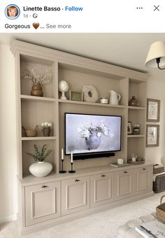 an entertainment center with built in shelving and vases on the shelves, along with a flat screen tv